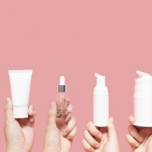 Hands holding up various skin care products